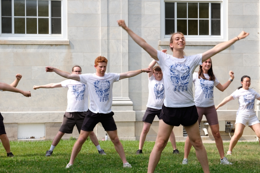 Students raise hands in the air triumphantly as they do a Japanese exercise outside. 