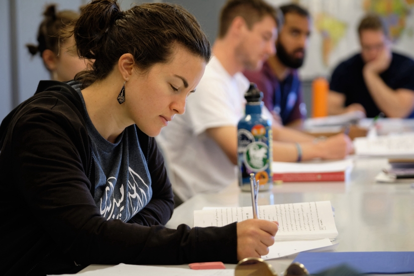 A student writes in her Arabic notebook in class. 