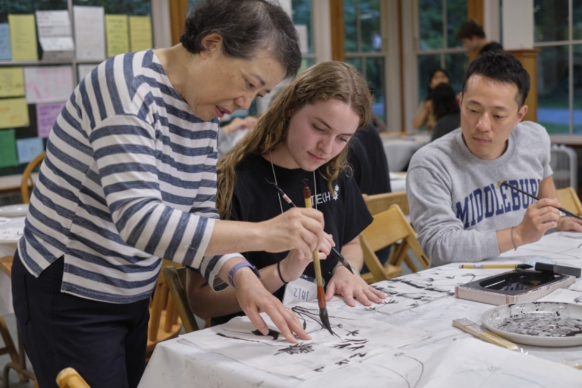 A teacher demonstrates how to paint Korean calligraphy on a fan. 