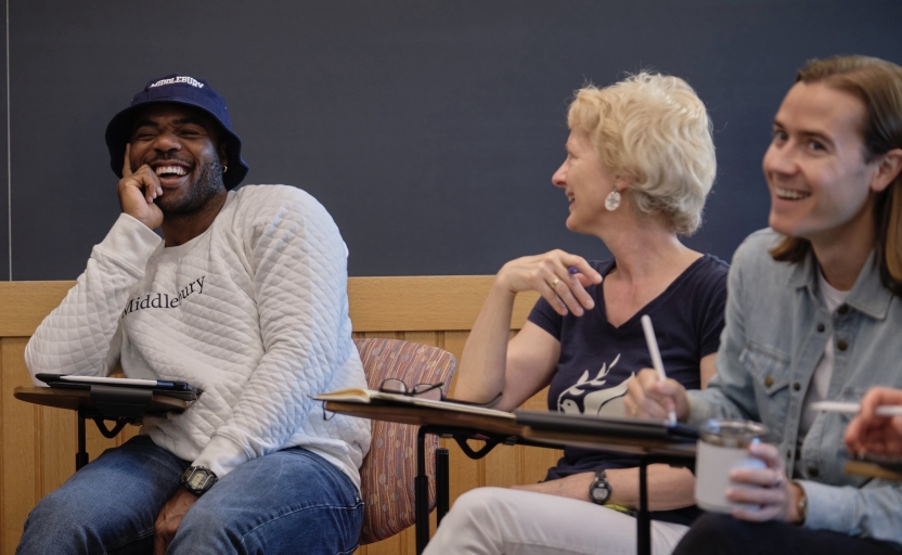 Students sit in class, laughing and smiling. 