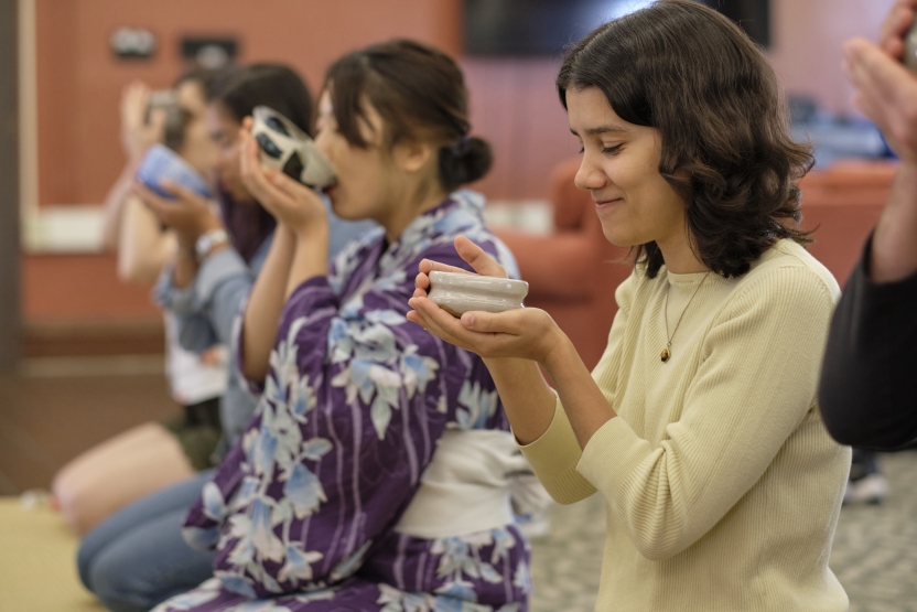 Students drink tea, sitting in a row. 