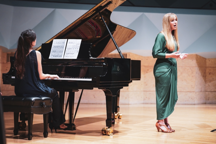 A singer and a pianist perform together on stage. 