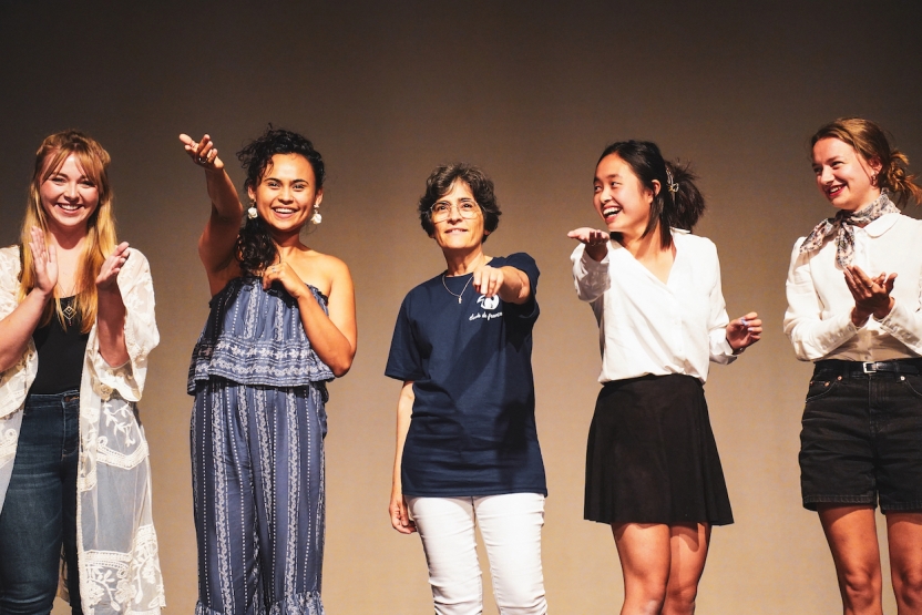 Students smile as they raise their hands in the air in a flourish.