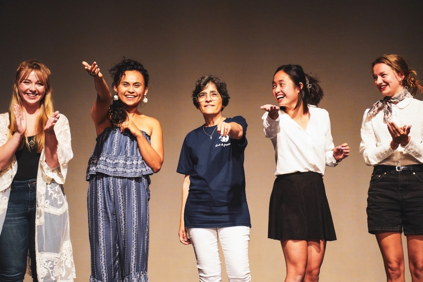 Students smile as they raise their hands in the air in a flourish. 