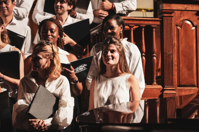 Students sing in a choir, smiling. 