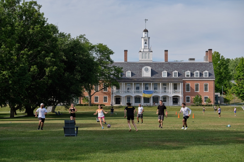 Students play soccer outside in the grass. 