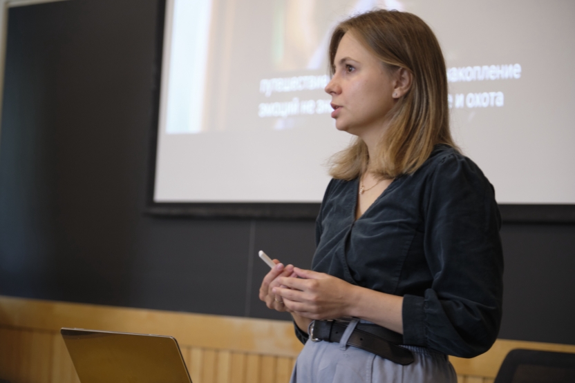 A teacher stands in front of a screen, speaking with her students. 