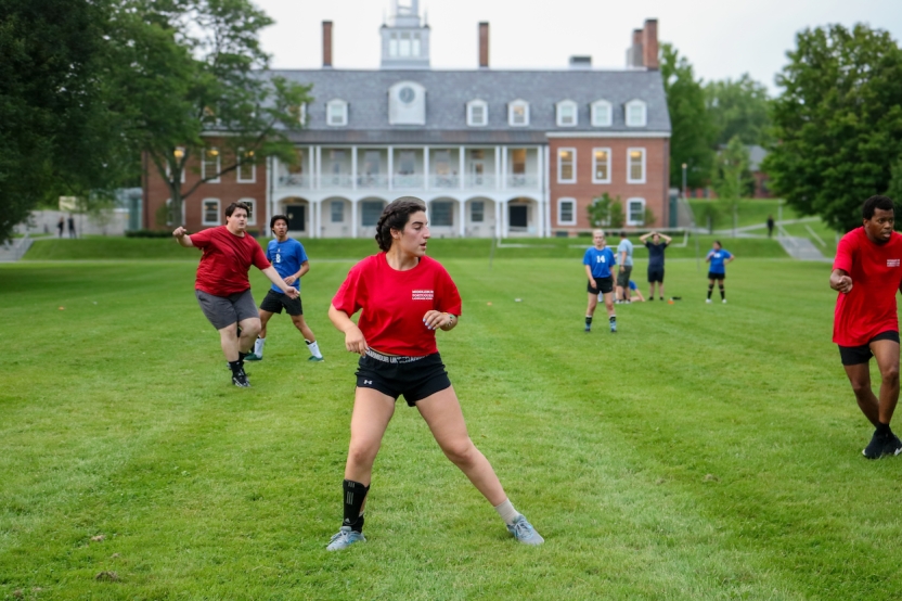 Students play soccer outside in red shirts. 