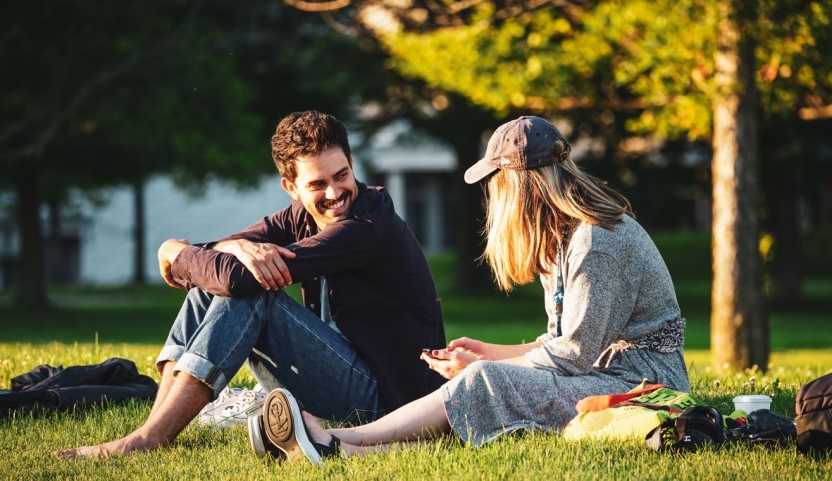 Two students on the grass enjoy the sunshine.