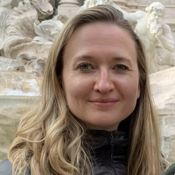 Tatyana smiles in front of a statue outside.