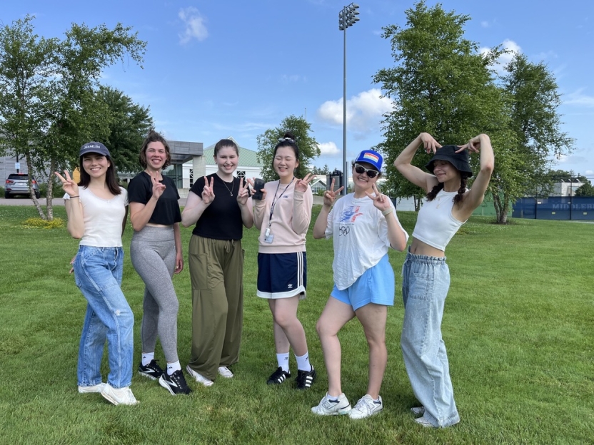 Students pose on the lawn, smiling. 