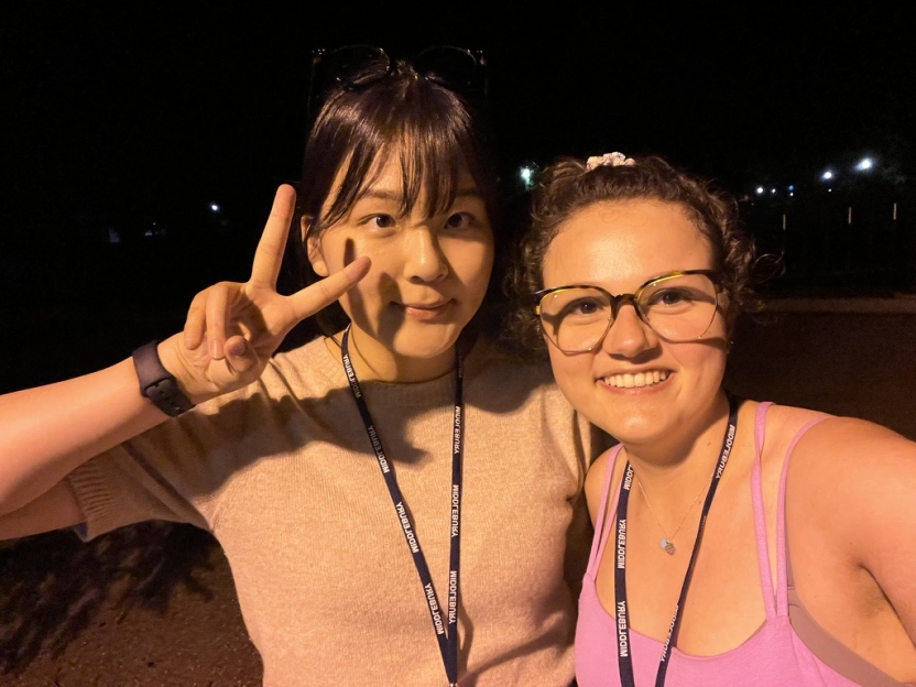 A student signs for "peace" next to a friend in a pink tank top. 