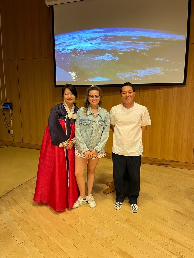 A student poses with her mentors in front of a screen. 