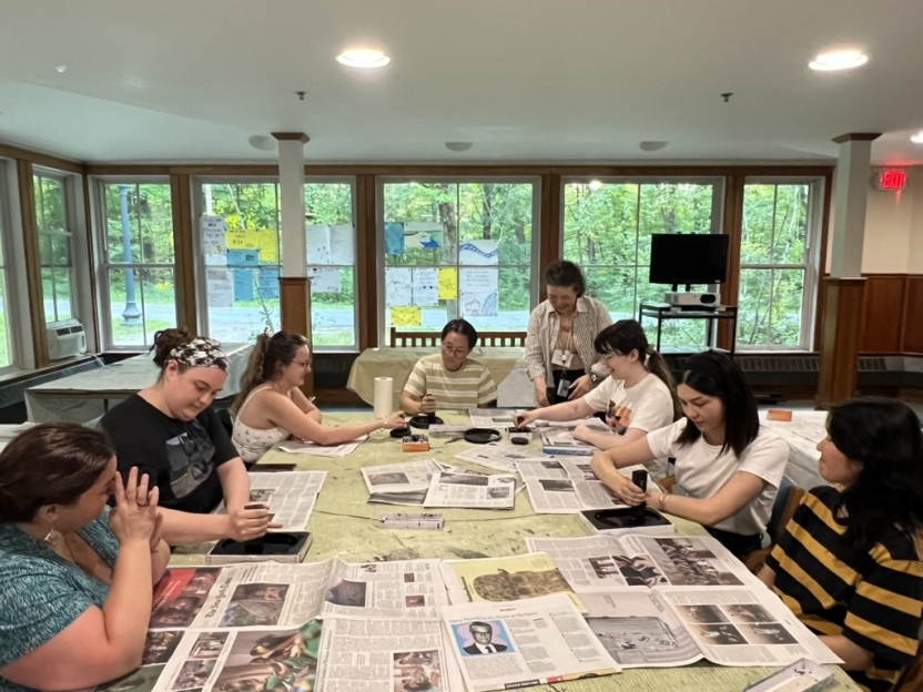 Students work on art at a conference table. 