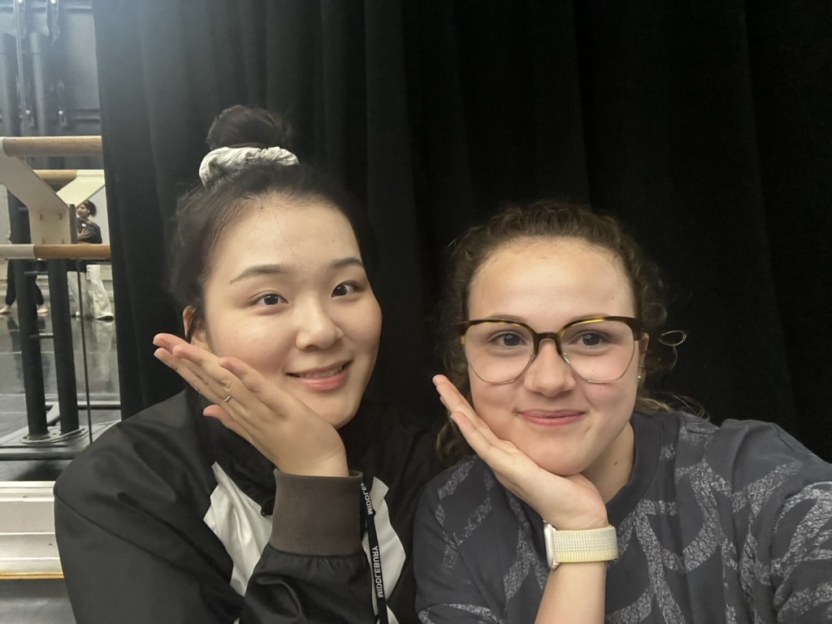 Two students smile with their hands open on their chins. 
