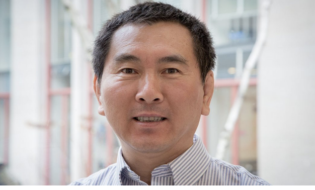 A man in a collared shirt smiles at the camera.