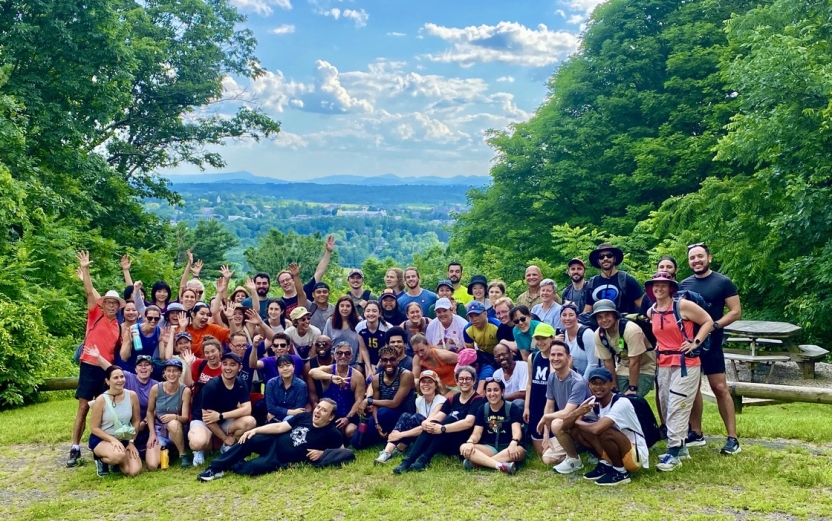 A group of student smiles in a group with mountains in the background.