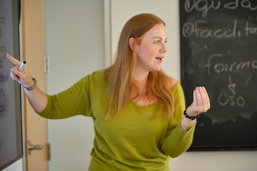 a teacher gestures and smiles at the blackboard. 