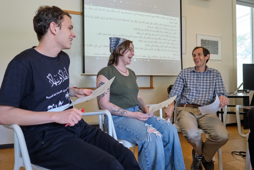 Students laugh in class, sitting at the front of the room. 