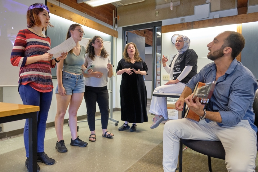 A student plays guitar while other students sing. 