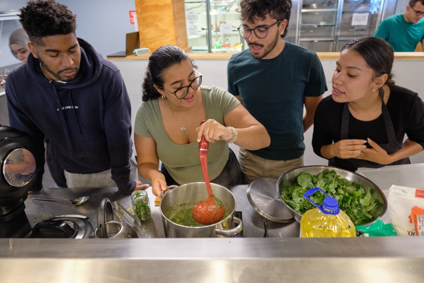Students ladle out their cooking together. 