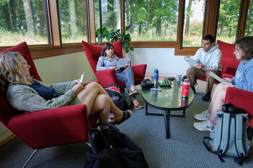 Students sit in red chairs in a circle for a class discussion.