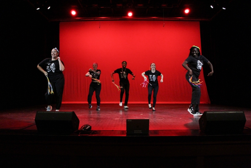 A group performs onstage in black clothing. 