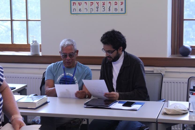 Two men look at Hebrew text together. 