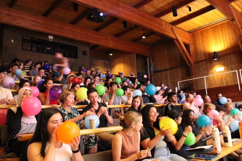 Students smile holding colorful balloons. 