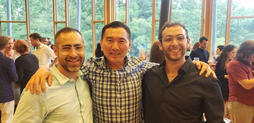 Three men smiling with their arms around each other. 