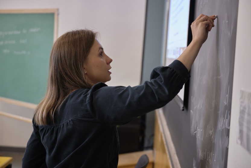 A teacher writes on the blackboard.