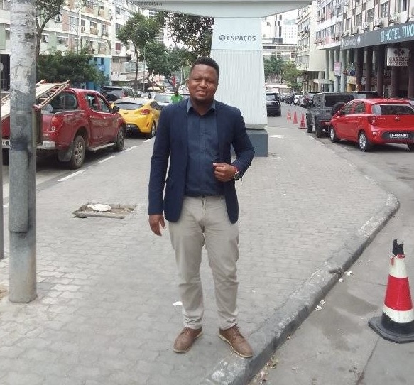 A man in a suit jacket stands on the sidewalk. 