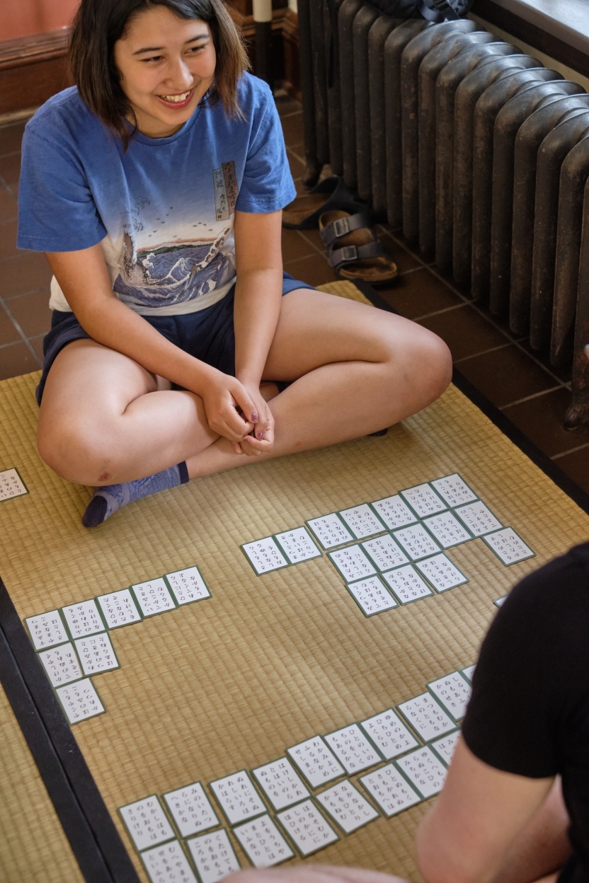 A student smiles as she plays a Japanese game. 