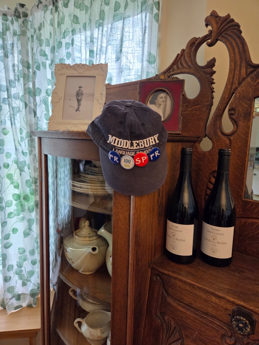 A hat with Language Schools pins on an antique secretary. 