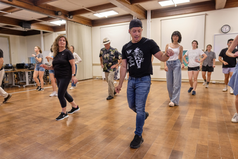 A group of students and staff participate in a dance class at the School of Spanish. 
