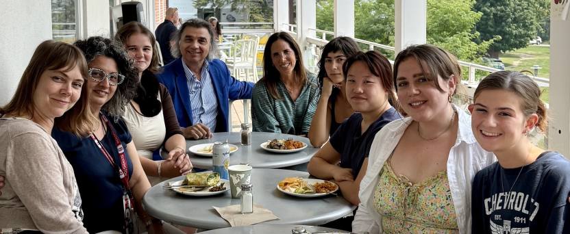 A group of Italian School students eat outside on a deck. 