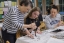 A teacher demonstrates how to paint Korean calligraphy on a fan.