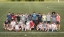 A group of students on a soccer team stands in a group, smiling.