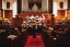 Students sing in a choir during the evening. A crowd watches.