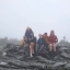 A group sits on a rock at the top of a rainy hike.