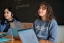 Two students sit smiling in Portuguese class. 