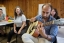 a student plays the guitar while another student listens, smiling.