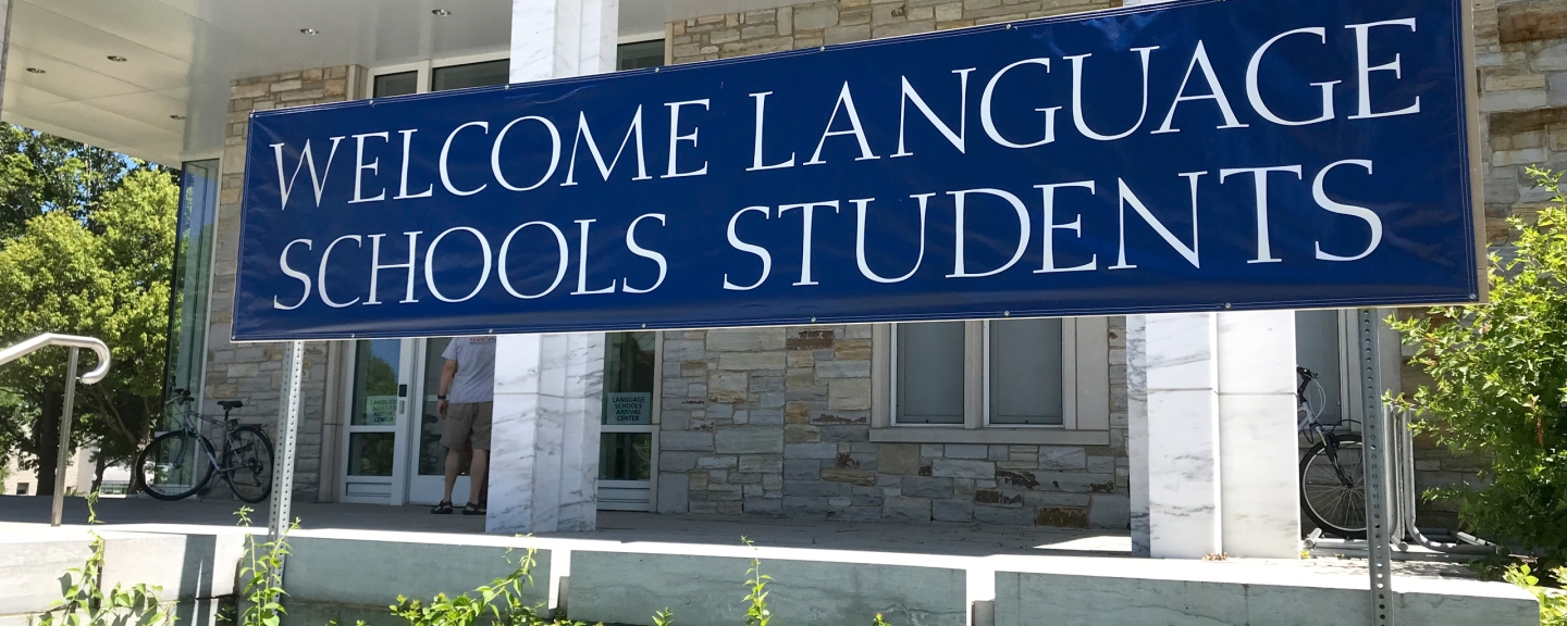 Banner hanging outside marble building reading "Welcome Language School Students"