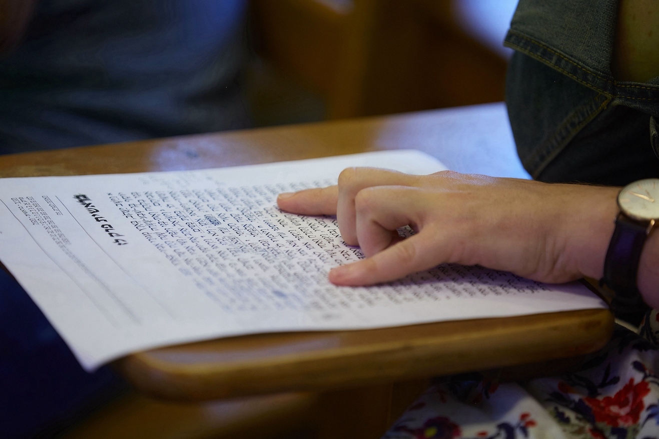A person runs their finger across a Hebrew document.