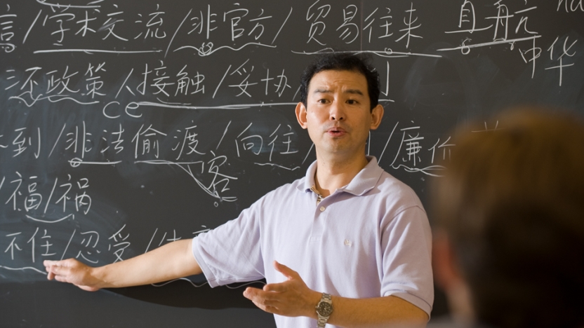 Japanese professor standing at chalkboard teaching students.