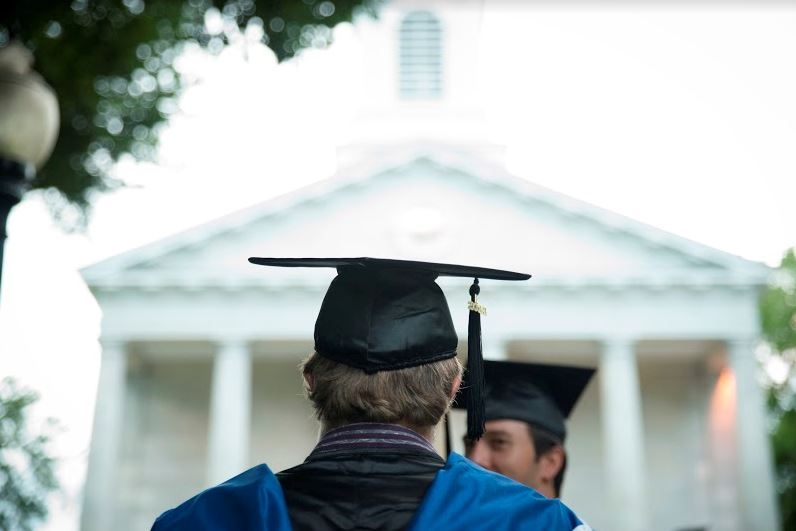A student with a graduation hat prepares to graduate.