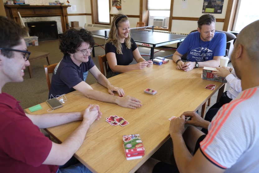 A group of people plays uno at a wooden table, smiling. 