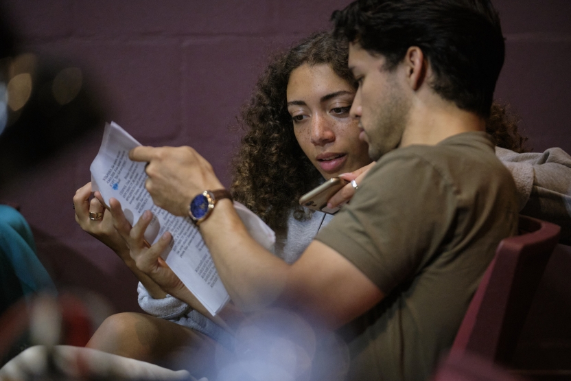 Two students examine the script of a play together. 
