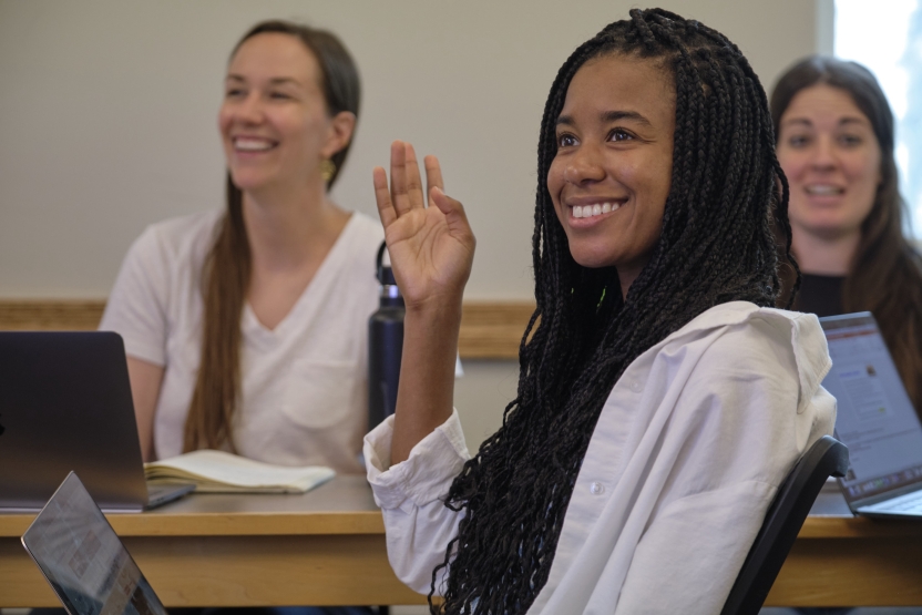 A student smiles as she raises her hands in class.