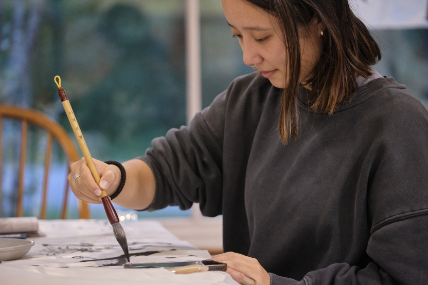A student paints with her calligraphy brush. 